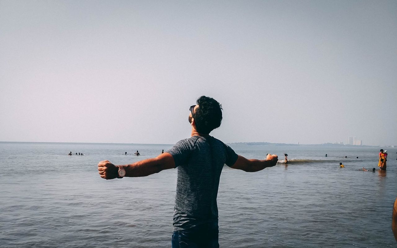estudiante en Nueva Zelanda con brazos abiertos frente al mar